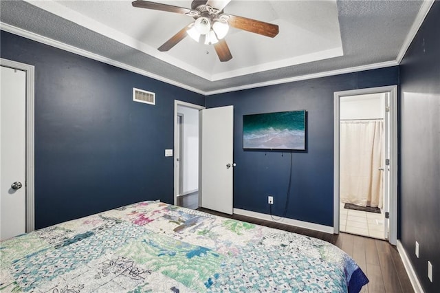 bedroom featuring ceiling fan, a raised ceiling, connected bathroom, crown molding, and dark hardwood / wood-style flooring