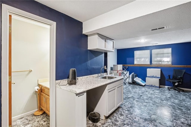 kitchen with white cabinets, a textured ceiling, and sink