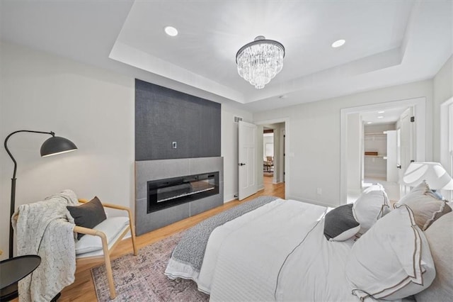 8301 Lee Blvd, Leawood, KS 66206 - bedroom featuring a raised ceiling, an inviting chandelier, a fireplace, recessed lighting, and wood finished floors