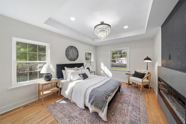 8301 Lee Blvd, Leawood, KS 66206 - bedroom featuring a tray ceiling, multiple windows, an inviting chandelier, and wood finished floors