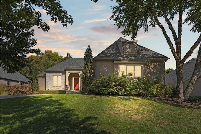 view of front of house with a front lawn, stone siding, and stucco siding