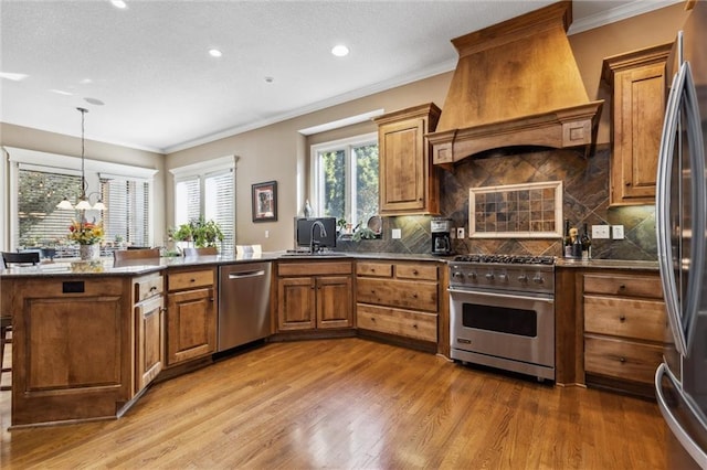 kitchen with decorative backsplash, sink, an inviting chandelier, stainless steel appliances, and custom range hood