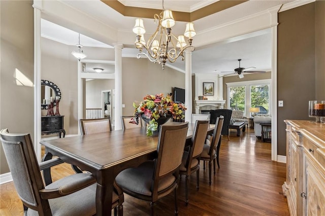 dining area featuring crown molding, ceiling fan with notable chandelier, dark hardwood / wood-style floors, and decorative columns