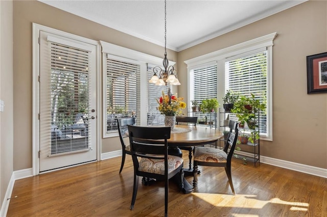 dining room with an inviting chandelier, crown molding, and hardwood / wood-style flooring