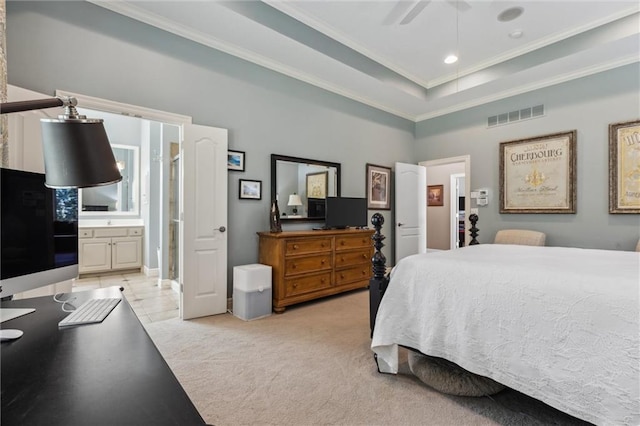 bedroom featuring visible vents, connected bathroom, crown molding, a tray ceiling, and light carpet