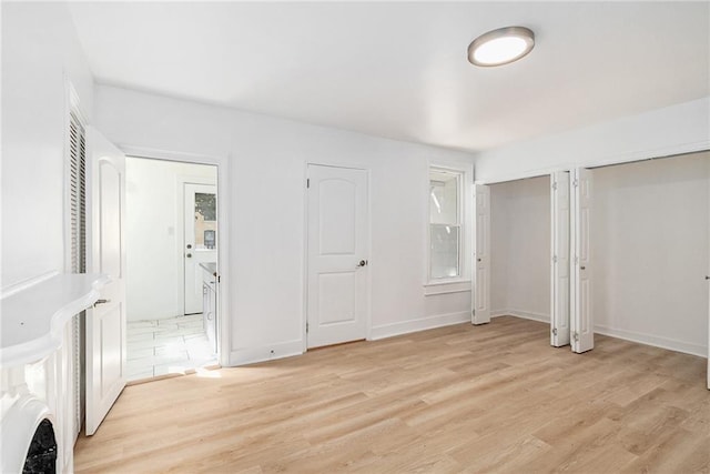 unfurnished bedroom featuring two closets and light hardwood / wood-style flooring