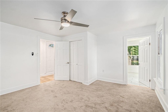 unfurnished bedroom with light carpet, a closet, and ceiling fan