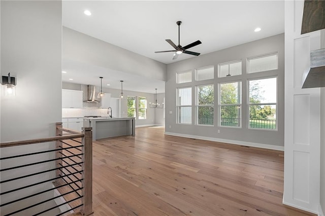 living room featuring light wood-type flooring, ceiling fan with notable chandelier, and sink