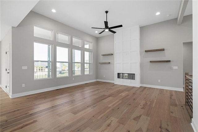 unfurnished living room featuring ceiling fan, beamed ceiling, and light wood-type flooring