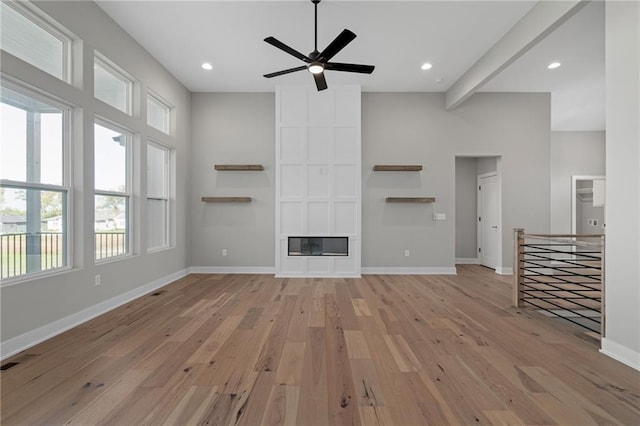 unfurnished living room with beam ceiling, light hardwood / wood-style floors, and ceiling fan