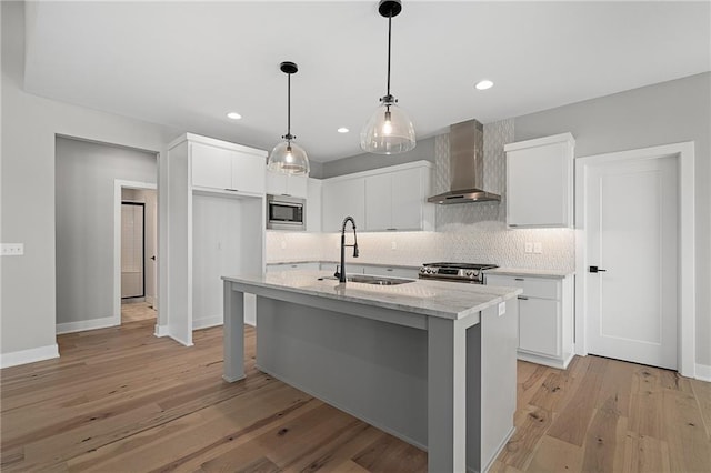 kitchen featuring white cabinets, sink, and wall chimney range hood