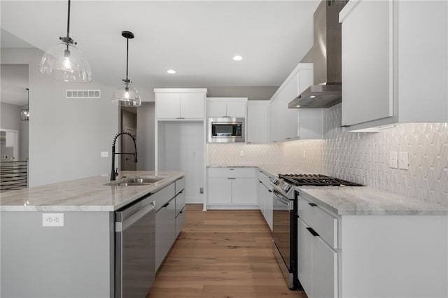 kitchen featuring wall chimney exhaust hood, stainless steel appliances, white cabinetry, and sink