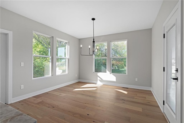 unfurnished dining area featuring a notable chandelier and light wood-type flooring