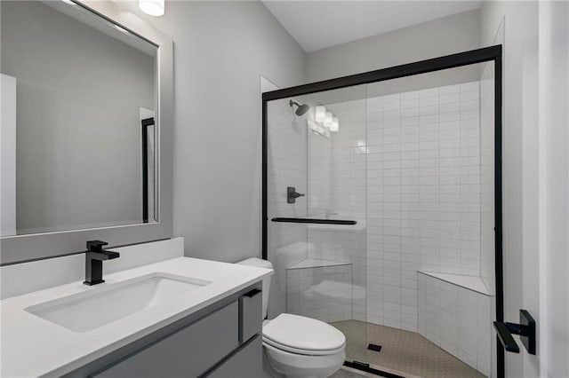 bathroom featuring vanity, a shower with shower door, and toilet