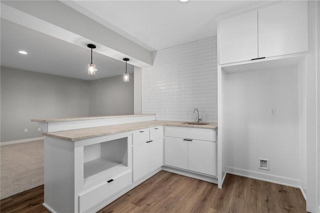 kitchen featuring dark hardwood / wood-style flooring, white cabinets, kitchen peninsula, and sink