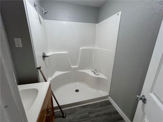 bathroom featuring walk in shower, vanity, and wood-type flooring