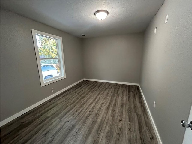 spare room with a textured ceiling and dark hardwood / wood-style floors