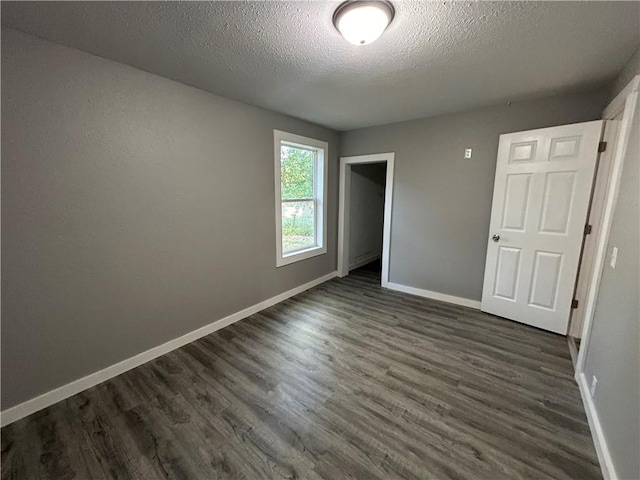 unfurnished bedroom featuring a textured ceiling and dark wood-type flooring