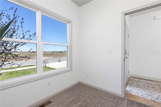 carpeted spare room featuring baseboards