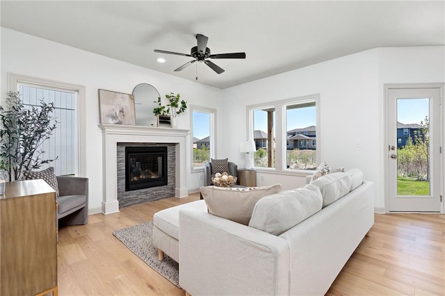 living area with ceiling fan, recessed lighting, baseboards, light wood-type flooring, and a glass covered fireplace