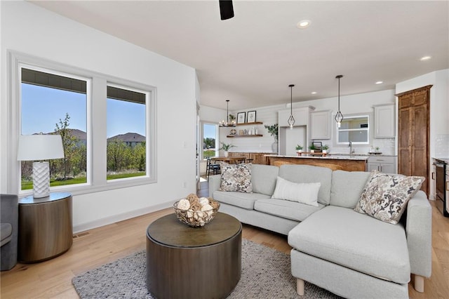 living room with light wood-style floors, recessed lighting, and baseboards