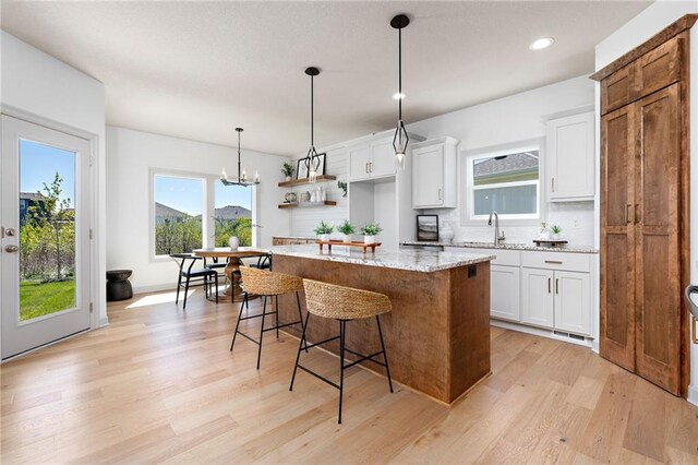 kitchen with light wood-type flooring, plenty of natural light, a kitchen bar, and a kitchen island