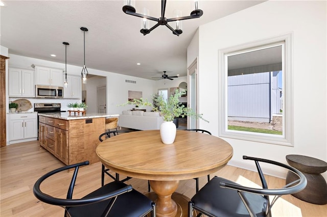 dining room featuring recessed lighting, ceiling fan with notable chandelier, visible vents, baseboards, and light wood-style floors