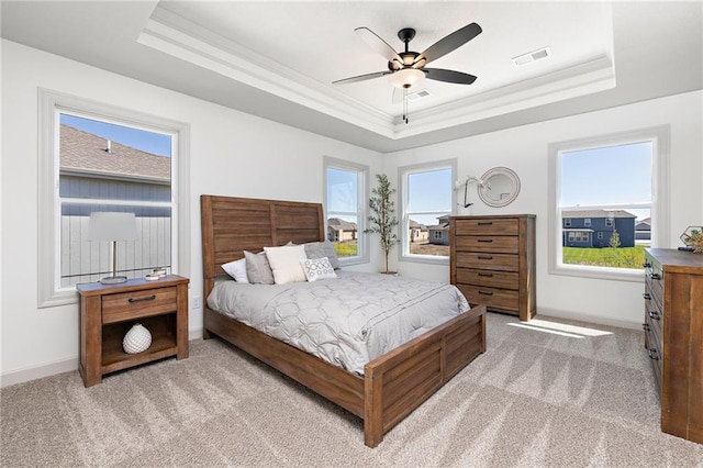 bedroom featuring ornamental molding, a raised ceiling, visible vents, and light carpet