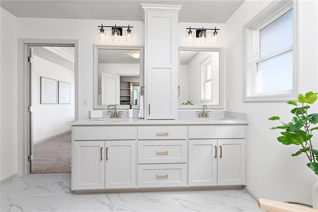 bathroom with marble finish floor, double vanity, a sink, and baseboards