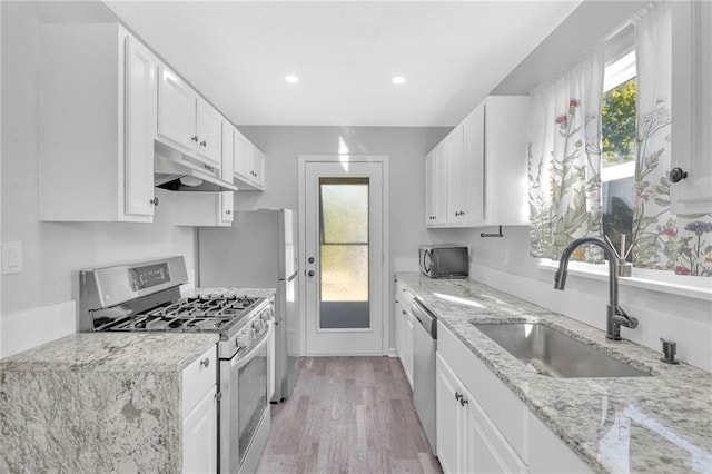 kitchen with sink, white cabinetry, appliances with stainless steel finishes, a healthy amount of sunlight, and light stone countertops