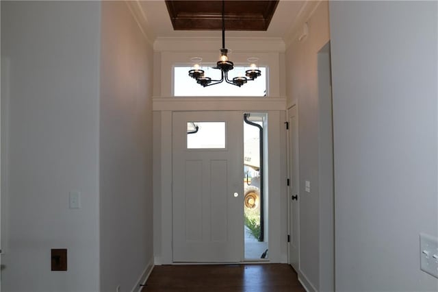 foyer with dark wood-type flooring, ornamental molding, and a healthy amount of sunlight