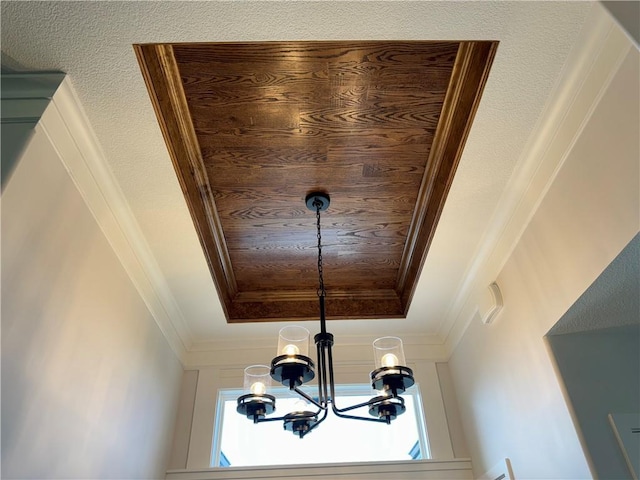 interior details with wood ceiling, ornamental molding, a tray ceiling, and a notable chandelier