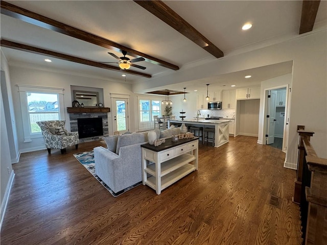 living room featuring dark hardwood / wood-style flooring, a fireplace, beam ceiling, and plenty of natural light