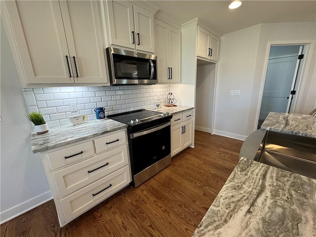 kitchen with light stone counters, appliances with stainless steel finishes, dark wood-type flooring, and white cabinets