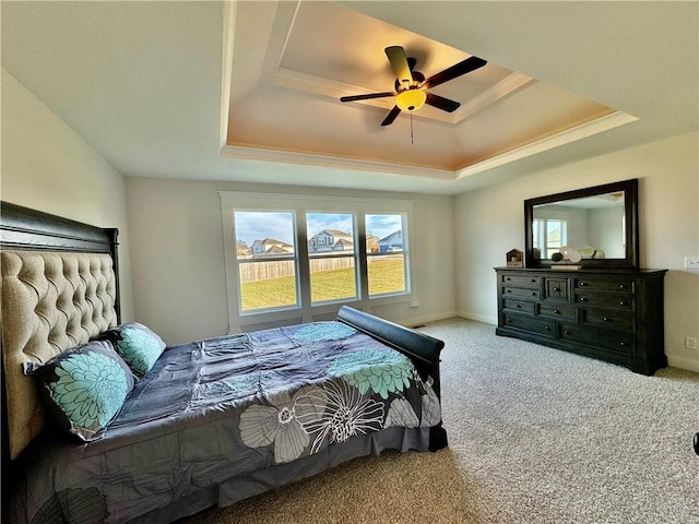 carpeted bedroom featuring ceiling fan and a raised ceiling