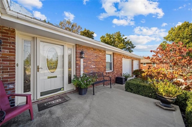 doorway to property featuring an attached garage and brick siding