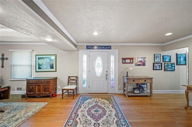 entrance foyer featuring a textured ceiling, visible vents, crown molding, wood finished floors, and recessed lighting