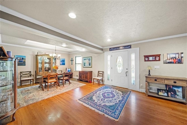 entrance foyer featuring crown molding, wood finished floors, baseboards, a textured ceiling, and a chandelier