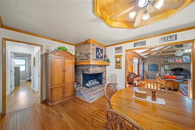 dining room with ceiling fan, crown molding, light hardwood / wood-style flooring, and a fireplace