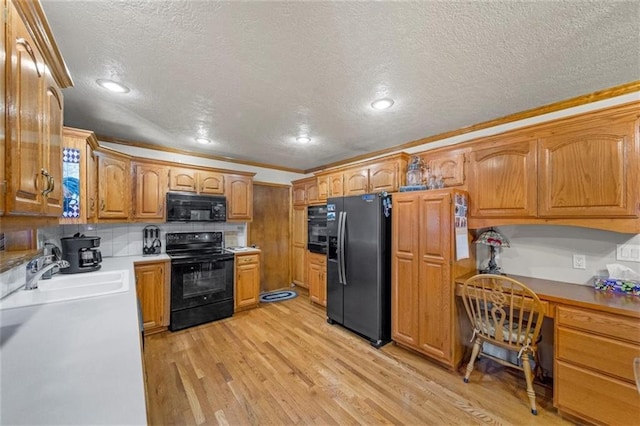 kitchen featuring a sink, a textured ceiling, black appliances, and ornamental molding