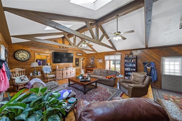 living room featuring beamed ceiling, wooden walls, hardwood / wood-style floors, a skylight, and ceiling fan