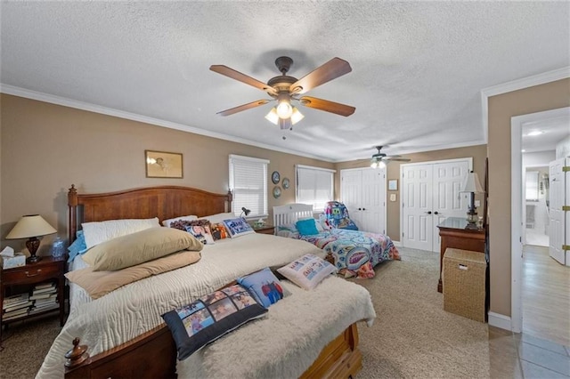 bedroom featuring baseboards, ornamental molding, two closets, and a textured ceiling