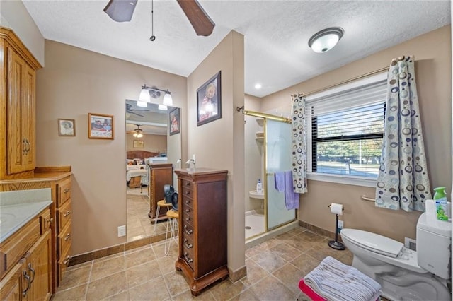 bathroom featuring vanity, toilet, baseboards, ceiling fan, and a shower stall