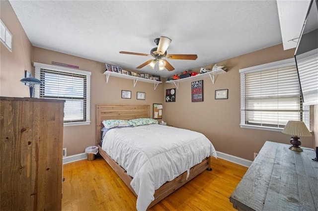 bedroom featuring a ceiling fan, baseboards, a textured ceiling, and light wood-type flooring