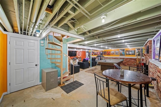 finished below grade area featuring stairway, billiards, and brick wall