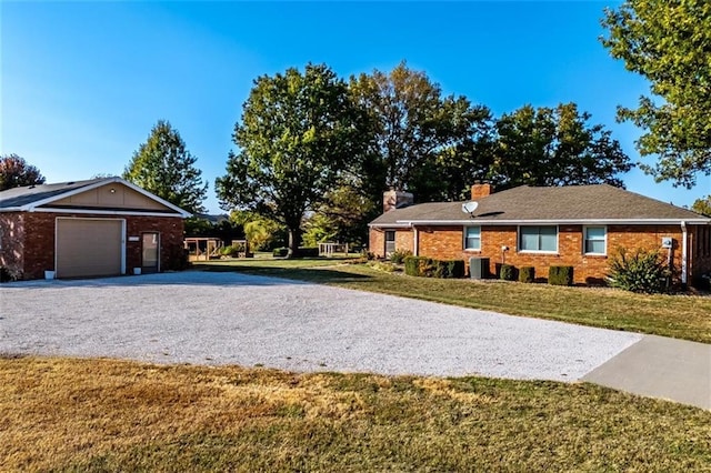 view of front of home featuring a chimney, a front lawn, central AC, and gravel driveway