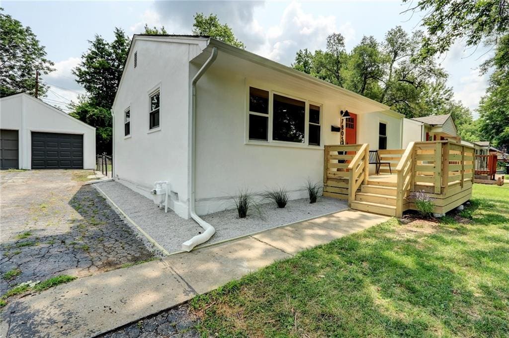 view of front facade featuring an outdoor structure, a garage, a wooden deck, and a front yard