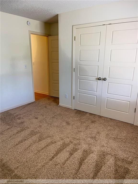 unfurnished bedroom with a textured ceiling, carpet, and a closet