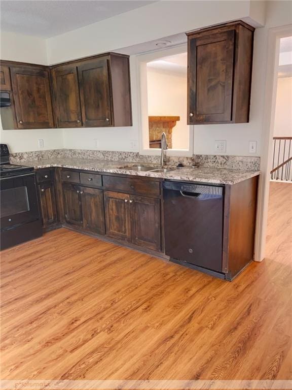 kitchen featuring dark brown cabinetry, sink, stainless steel dishwasher, light hardwood / wood-style flooring, and black / electric stove