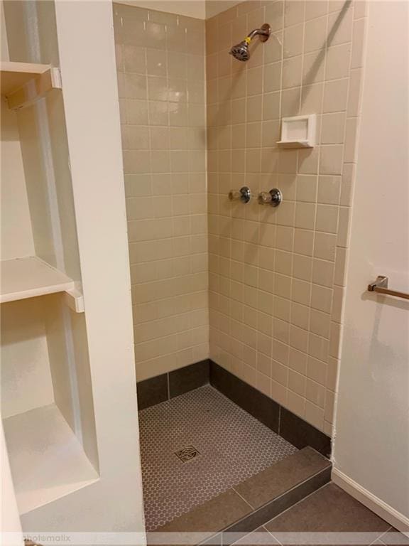 bathroom featuring tiled shower and tile patterned flooring